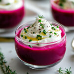 Verrine de gaspacho de betterave surmontée d’une chantilly au chèvre frais et parsemée de ciboulette, plat d'été coloré et raffiné.