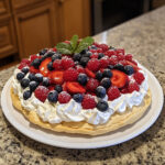 Pavlova maison garnie de chantilly et fruits rouges frais, dressée sur assiette blanche, dessert léger et coloré.