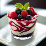 Verrine de yaourt onctueux marbré au coulis de fruits rouges, décorée de fraises, framboises et myrtilles fraîches.